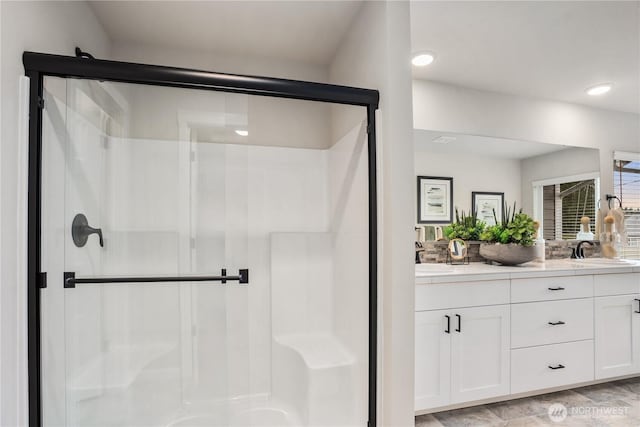 bathroom featuring double vanity, a stall shower, and a sink