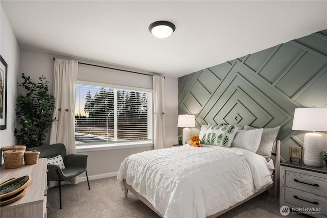 carpeted bedroom featuring an accent wall and baseboards