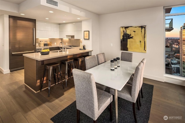 dining space with sink, dark hardwood / wood-style floors, and a wall of windows