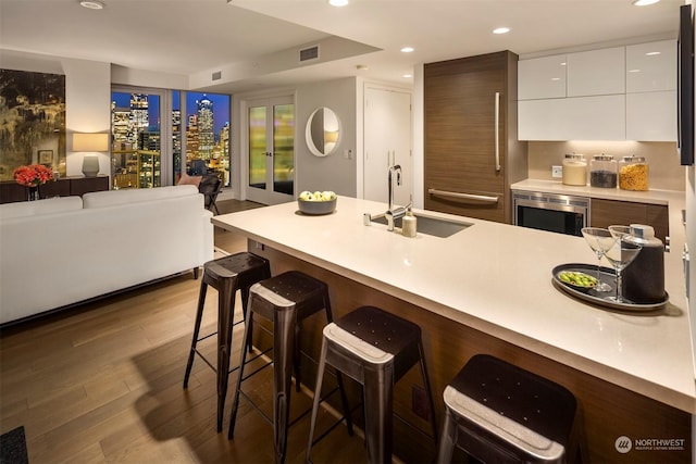 kitchen with stainless steel microwave, sink, white cabinets, dark wood-type flooring, and a breakfast bar