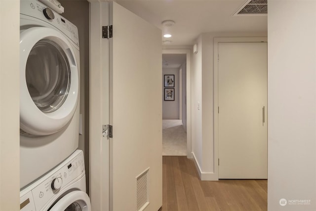 washroom with light hardwood / wood-style floors and stacked washer and dryer