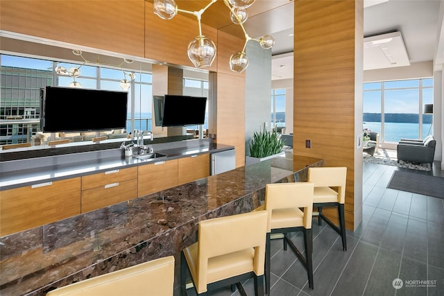 kitchen with a wealth of natural light, dishwasher, sink, hanging light fixtures, and a breakfast bar area