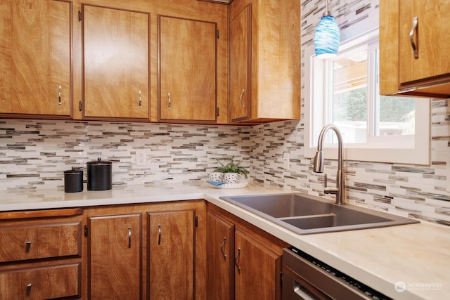 kitchen with tasteful backsplash, dishwasher, sink, and hanging light fixtures