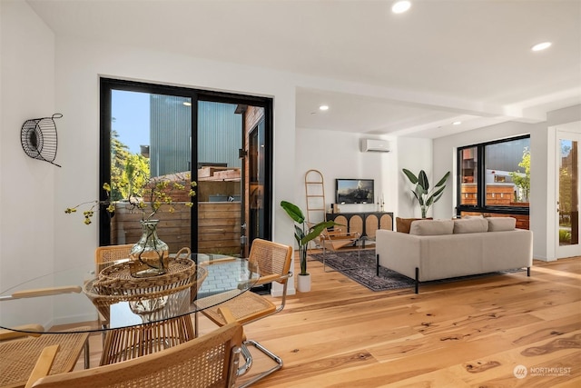 living room with beam ceiling, light hardwood / wood-style flooring, and a wall mounted air conditioner