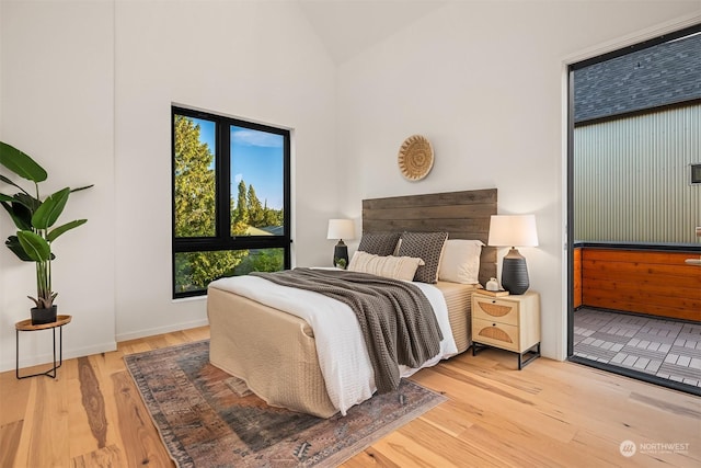 bedroom with high vaulted ceiling and light wood-type flooring