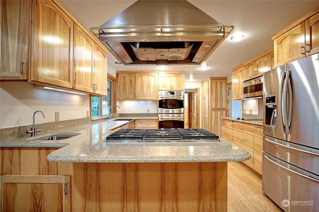 kitchen with light stone countertops, kitchen peninsula, appliances with stainless steel finishes, and a tray ceiling