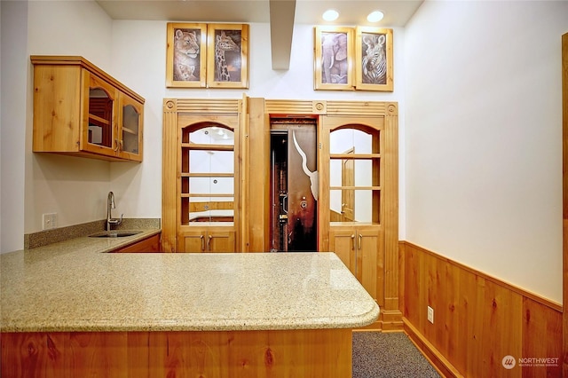 kitchen with kitchen peninsula, sink, and wooden walls