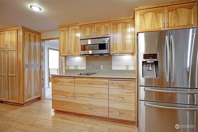 kitchen with light brown cabinetry, backsplash, light hardwood / wood-style flooring, and stainless steel appliances