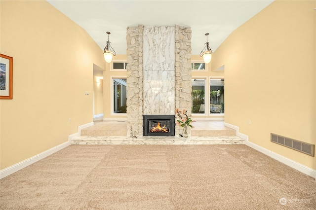 unfurnished living room with vaulted ceiling, light colored carpet, and a stone fireplace