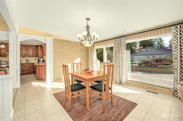 dining area featuring light tile patterned floors, an inviting chandelier, and decorative columns