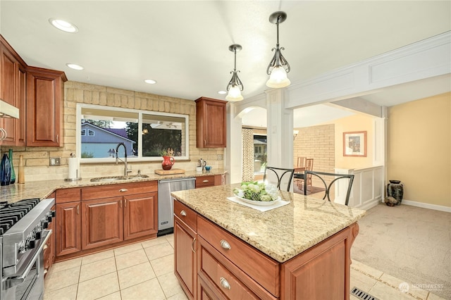 kitchen with appliances with stainless steel finishes, a kitchen island, pendant lighting, light stone counters, and sink