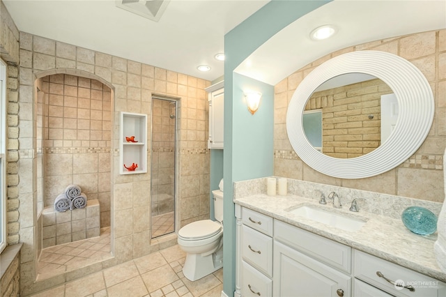 bathroom featuring tile walls, toilet, vanity, and a tile shower