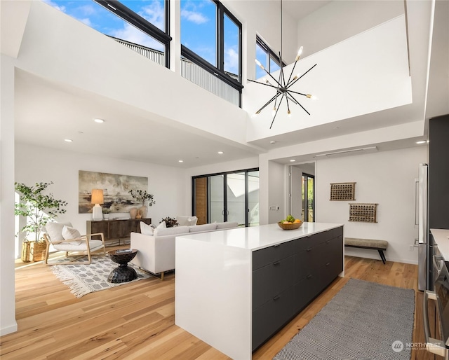 kitchen with plenty of natural light, a large island, a notable chandelier, and light wood-type flooring