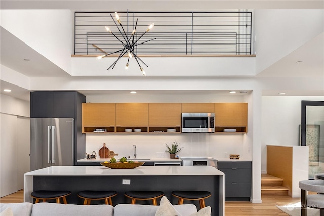 kitchen with a breakfast bar, appliances with stainless steel finishes, a high ceiling, and a center island