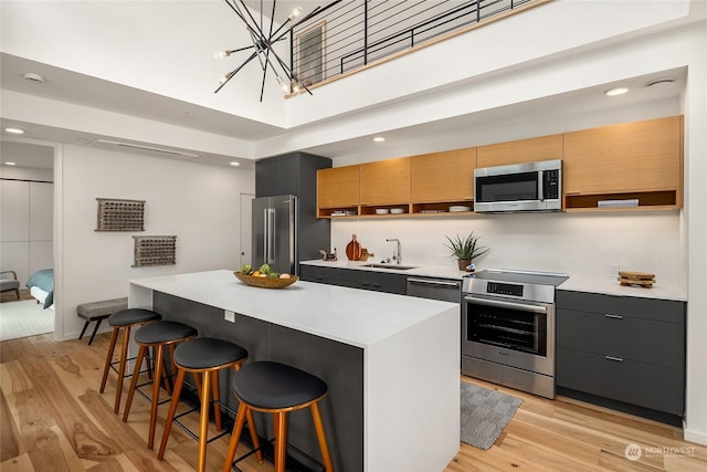 kitchen with a center island, a breakfast bar, sink, stainless steel appliances, and a chandelier