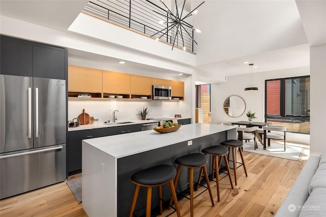 kitchen featuring pendant lighting, appliances with stainless steel finishes, a center island, a kitchen bar, and sink