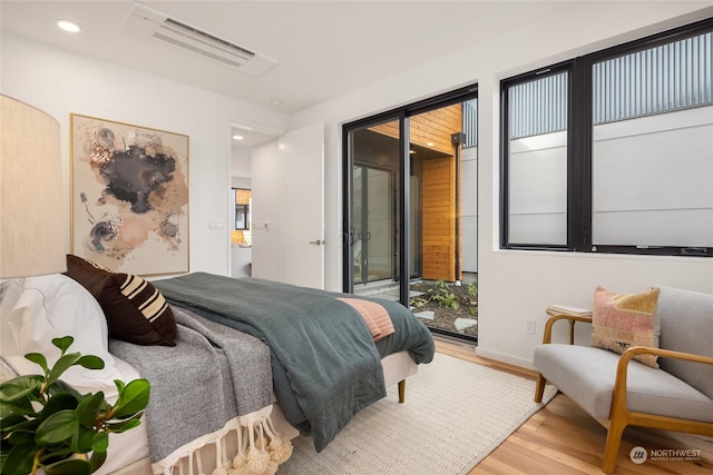 bedroom with access to outside and hardwood / wood-style floors