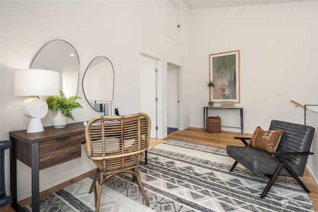 sitting room with a high ceiling and hardwood / wood-style flooring