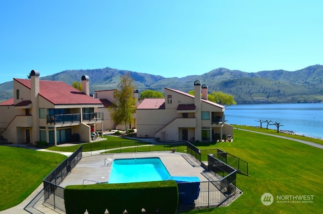 view of pool with a patio, a water and mountain view, and a yard