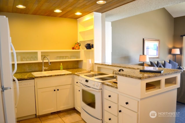 kitchen with kitchen peninsula, white appliances, stone counters, white cabinets, and sink