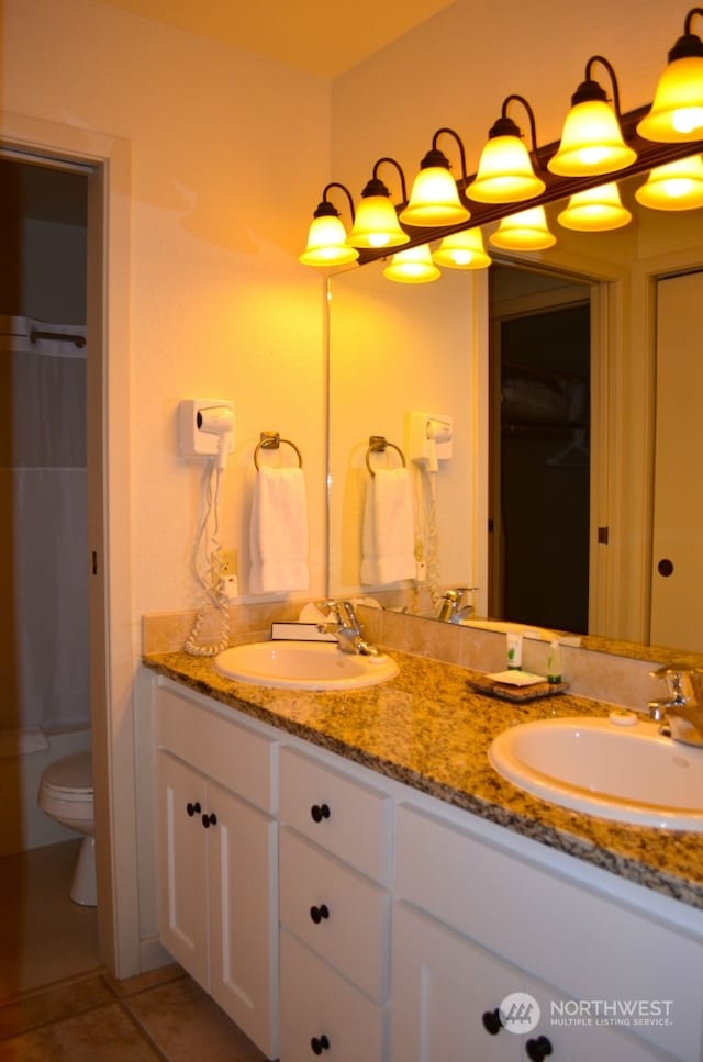 bathroom with toilet, vanity, and tile patterned flooring