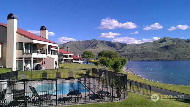 view of pool with a water and mountain view and a lawn