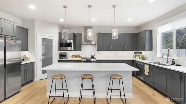 kitchen with wall chimney exhaust hood, sink, stainless steel appliances, and a center island