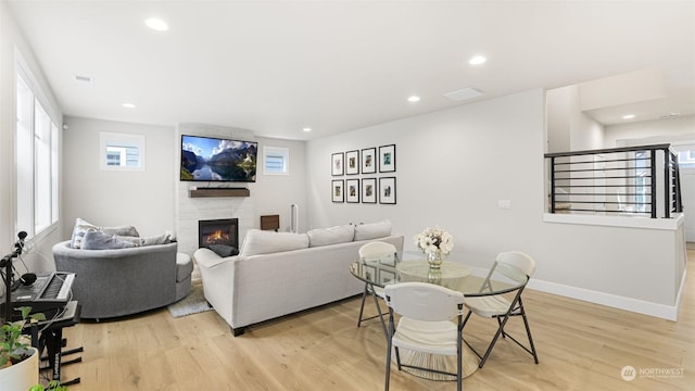 living room with a tile fireplace and light hardwood / wood-style flooring