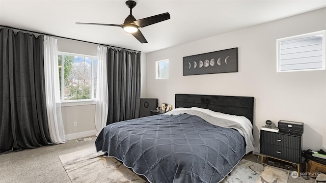 bedroom with ceiling fan, light carpet, and multiple windows