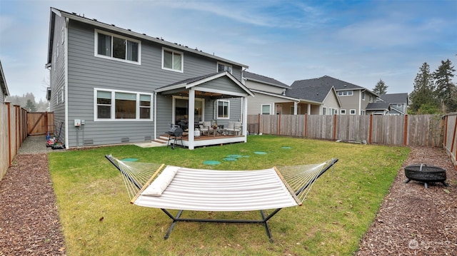 back of house with a wooden deck, a yard, and a fire pit