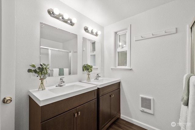 bathroom with hardwood / wood-style flooring, heating unit, a shower with door, and vanity