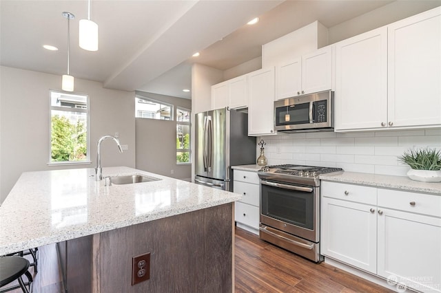 kitchen with pendant lighting, appliances with stainless steel finishes, white cabinetry, tasteful backsplash, and sink