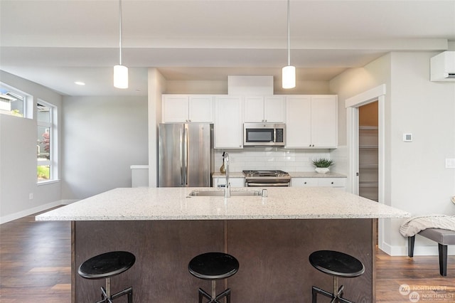 kitchen featuring stainless steel appliances, backsplash, white cabinets, and decorative light fixtures