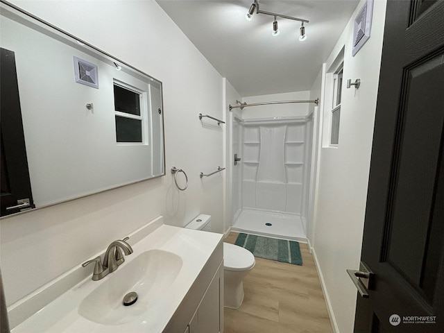 bathroom featuring toilet, vanity, a shower, and hardwood / wood-style floors