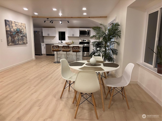 dining area with sink, light hardwood / wood-style flooring, and track lighting