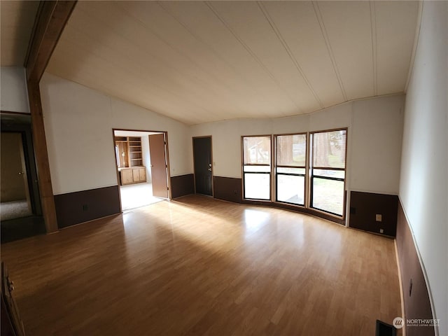 spare room with vaulted ceiling and light hardwood / wood-style flooring