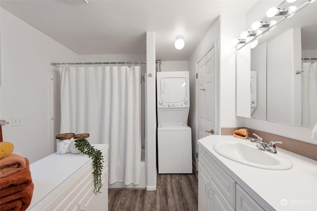 bathroom with hardwood / wood-style flooring, shower / bath combination with curtain, stacked washer and dryer, and vanity