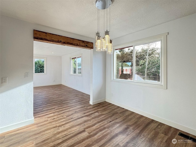 unfurnished dining area featuring hardwood / wood-style floors, beamed ceiling, a textured ceiling, and a notable chandelier