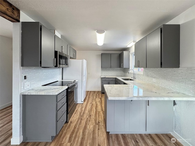 kitchen featuring electric stove, tasteful backsplash, kitchen peninsula, sink, and gray cabinetry