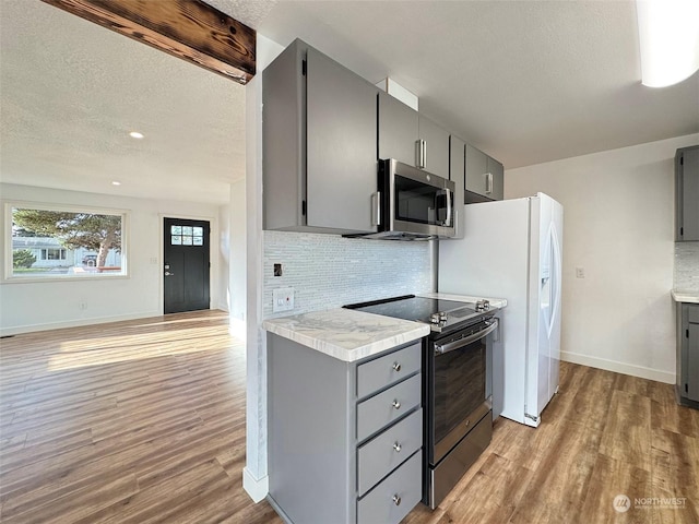 kitchen with tasteful backsplash, gray cabinetry, stainless steel appliances, and light hardwood / wood-style flooring