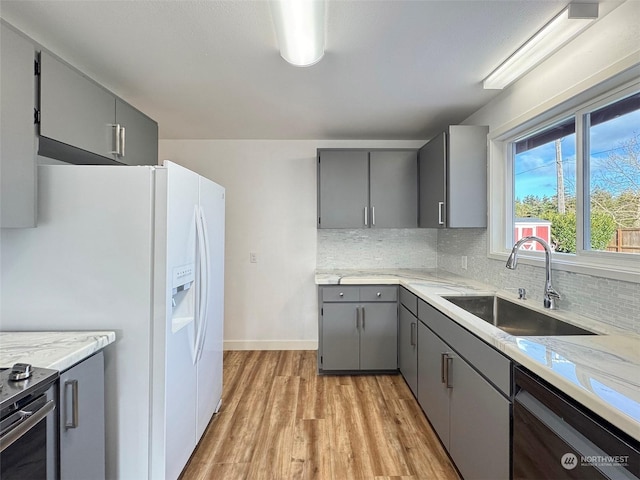 kitchen with gray cabinets, dishwasher, white refrigerator with ice dispenser, light hardwood / wood-style flooring, and sink