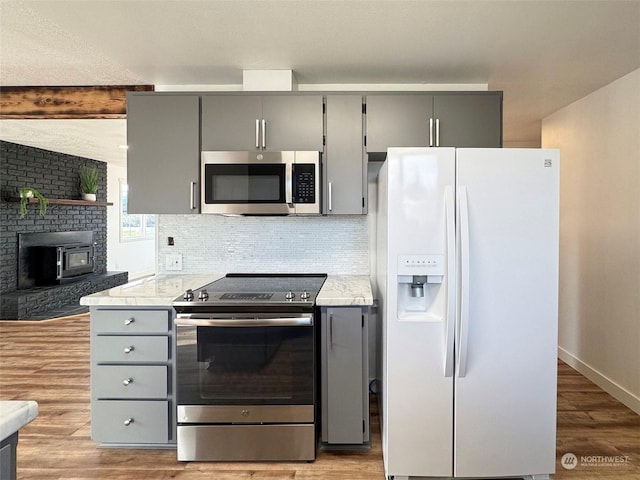 kitchen with tasteful backsplash, light wood-type flooring, gray cabinets, and stainless steel appliances