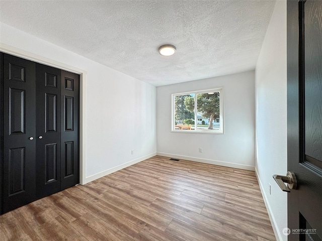 interior space with a textured ceiling and light hardwood / wood-style flooring