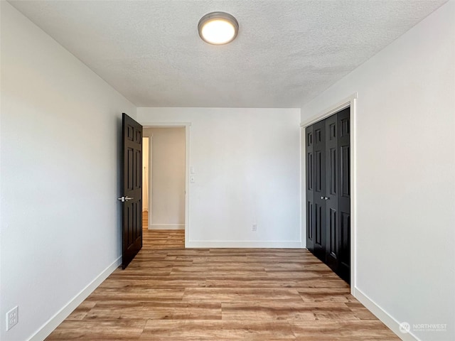 spare room with light hardwood / wood-style floors and a textured ceiling