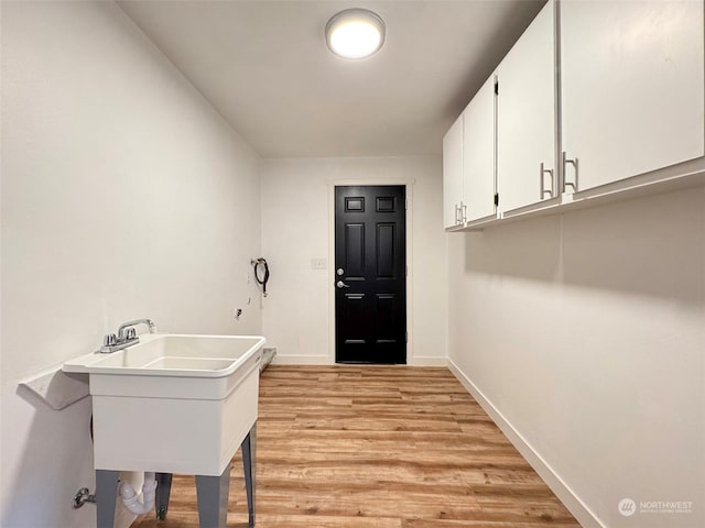 laundry area featuring cabinets, sink, and light hardwood / wood-style floors