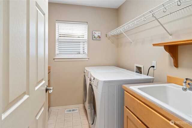 clothes washing area with cabinets, light tile patterned flooring, washer and dryer, and sink