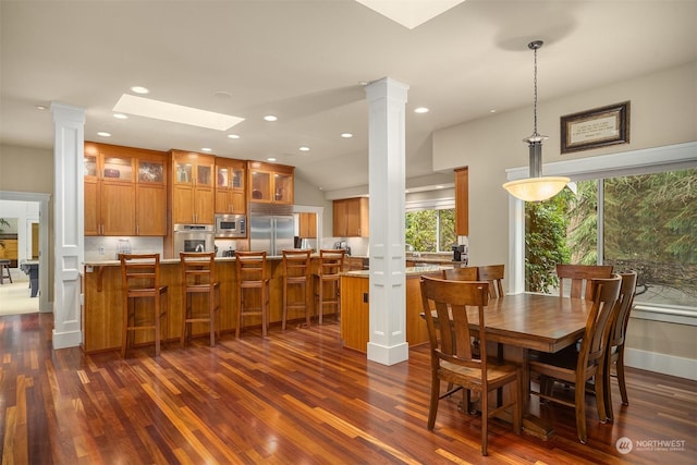 dining space featuring dark wood-type flooring, ornate columns, and plenty of natural light