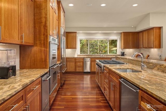 kitchen with stainless steel appliances, sink, decorative backsplash, and light stone countertops