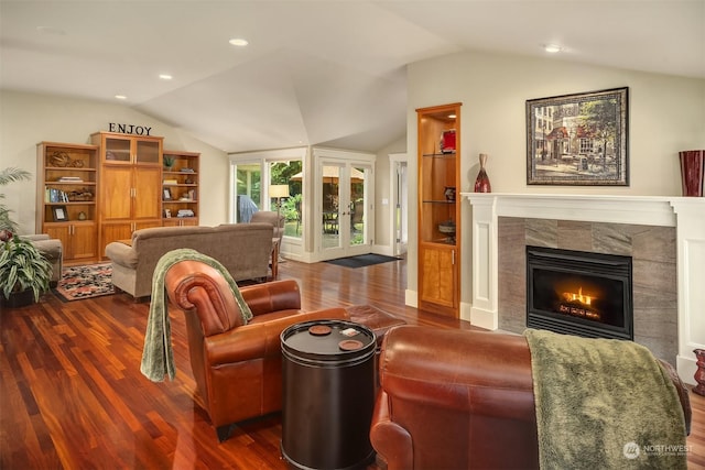 living room featuring hardwood / wood-style floors, a tile fireplace, and vaulted ceiling