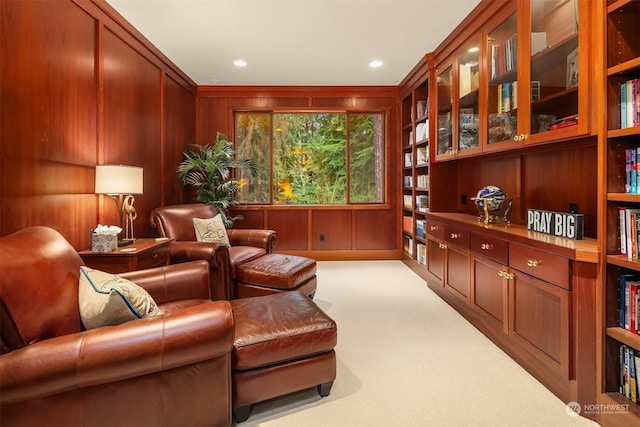 living area with light carpet and wooden walls